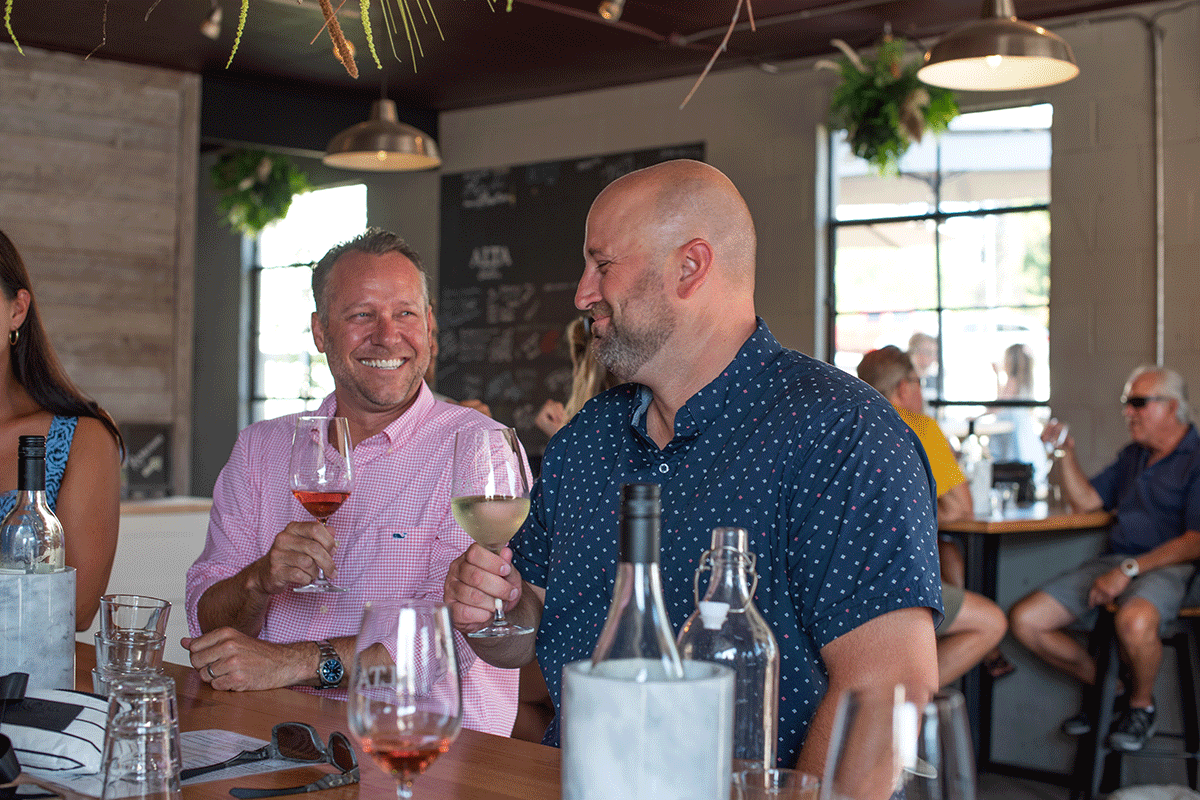 Two men drinking wine and smiling at Alta Cellars